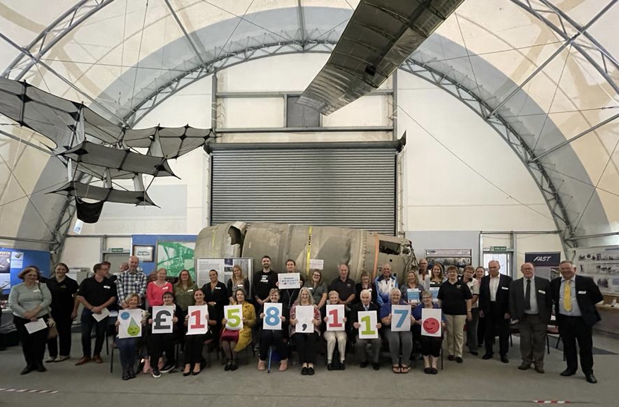 Guests at the Rushmoor Community Lottery fifth anniversary celebration, holding up cards with the grant total of £158,117.